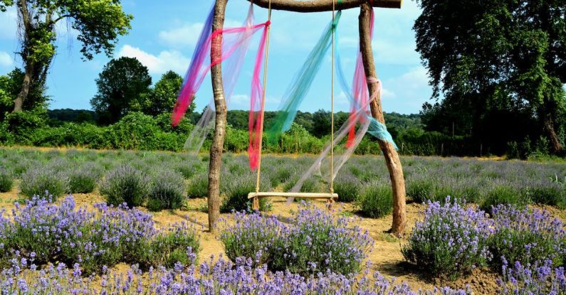 Summer Fabrics - Wooden Swing Decorated with Translucent Fabrics Standing amid Blooming Lavender