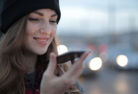 Travel Apps - Joyful young woman phoning on street in evening