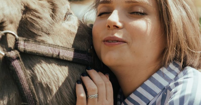 Pet - Woman in Blue and White Striped Long Sleeve Shirt Holding Black Horse