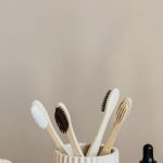 Sustainable Alternatives - Collection of bamboo toothbrushes and organic natural soaps with wooden body brush arranged with recyclable glass bottle with natural oil and ceramic vase with artificial plant